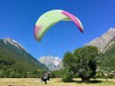 Tandem paraglider landing in field next to Alpbase